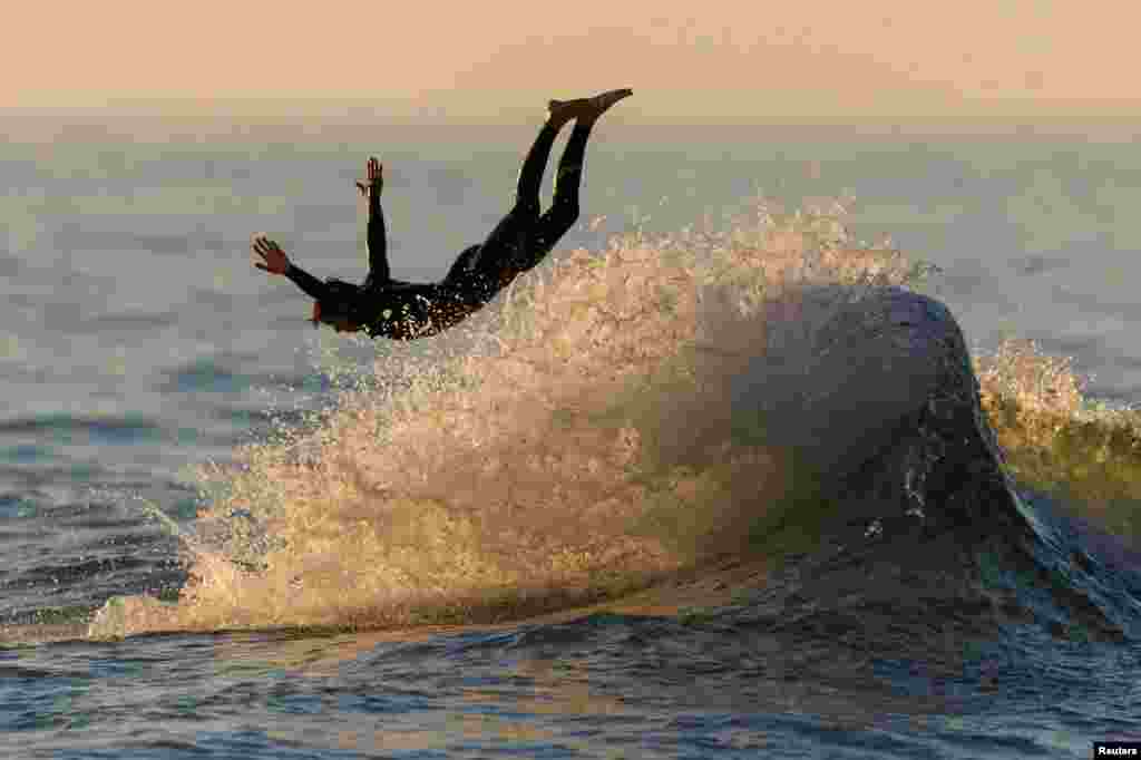 A surfer dives off his board while riding the waves at sunset in Encinitas, California, Aug. 28, 2023.