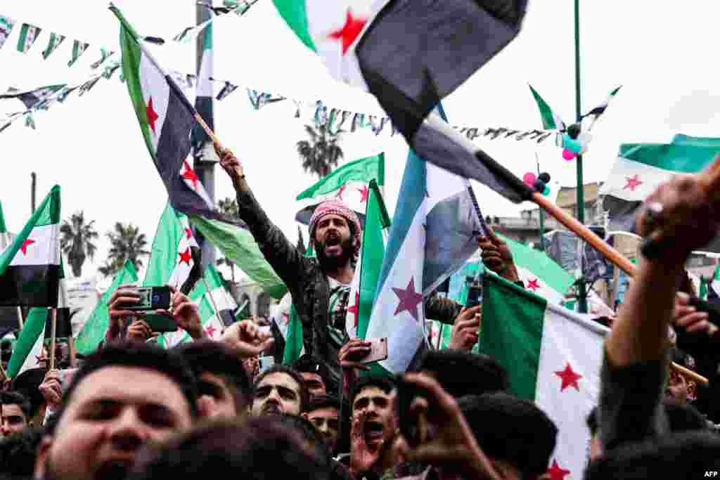 People chant slogans and wave flags of the Syrian opposition during a rally marking the 12th anniversary of the start of the uprising against Syrian President Bashar al-Assad and his government, in the rebel-held northwestern city of Idlib.