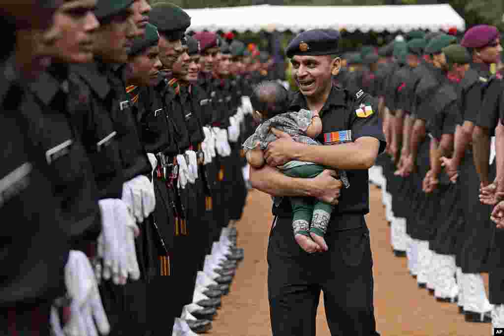 An Indian Army soldier carrying his baby reacts as he walks past graduating soldiers from the first batch of Agniveer scheme during their graduation ceremony in Bengaluru, India. Agniveer, a new short-term job program announced by the government for the military, was launched in June 2022. 