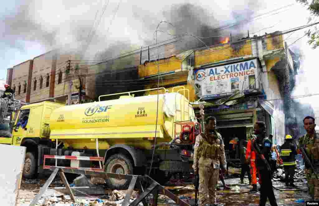 Somali police stand guard after an explosion at a shopping mall area that caused fire at the Bakara market in Mogadishu.