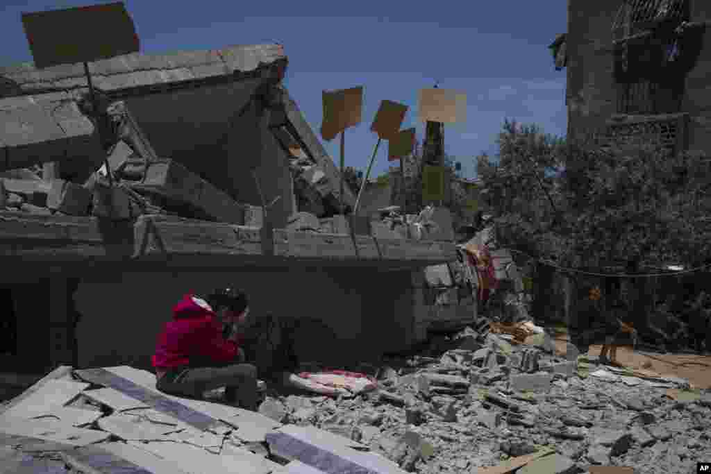 Jalal Nabhan and relatives sit in front of the ruins of their home, which was destroyed in an Israeli airstrike, in Jabaliya, northern Gaza Strip, May 14, 2023.