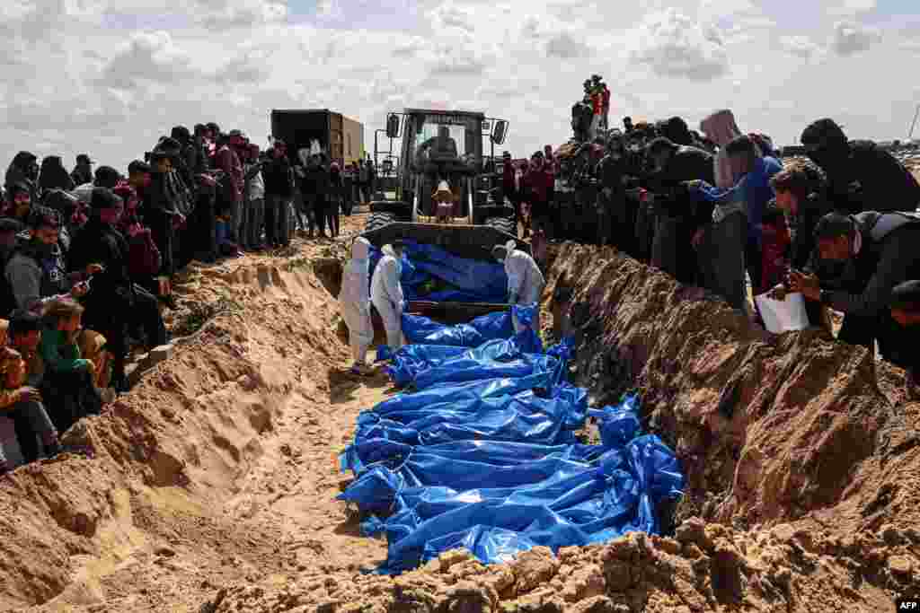 Mourners watch as medical personnel prepare the bodies of 47 Palestinians, that were taken and later released by Israel, during a mass funeral in Rafah in the southern Gaza Strip.