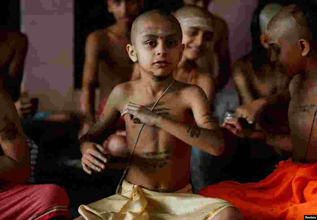 A novice Hindu priest applies cow dung on his body as part of a ritual performed to mark the Janai Purnima festival (Sacred Thread Festival) during which devotees take holy baths and change their sacred thread, also known as Janai, for protection and purification, at the premises of Pashupatinath Temple in Kathmandu, Nepal. 