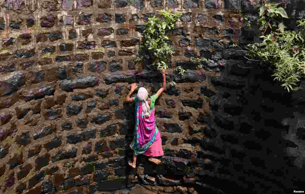 Suman Bhutambare attempts to climb up a well after retrieving a friend's sieve that fell into the well, in Telamwadi near Mumbai, India.