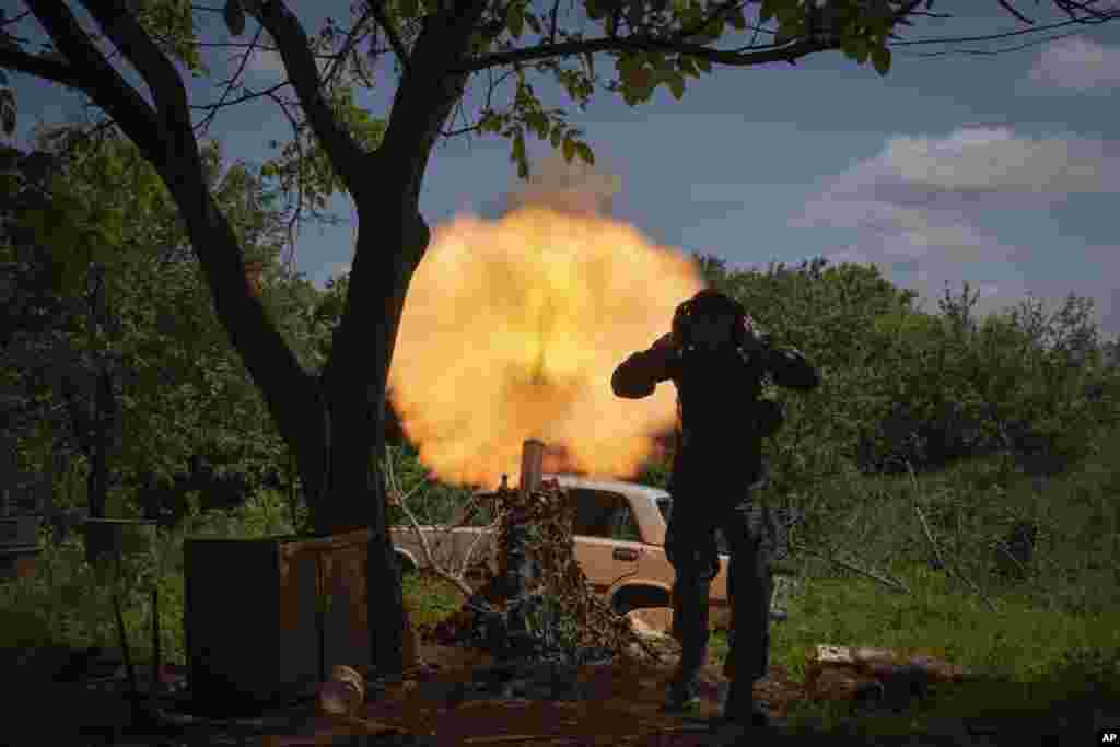 A Ukrainian soldier covers his ears while firing a mortar at Russian positions on the frontline near Bakhmut, Donetsk region.