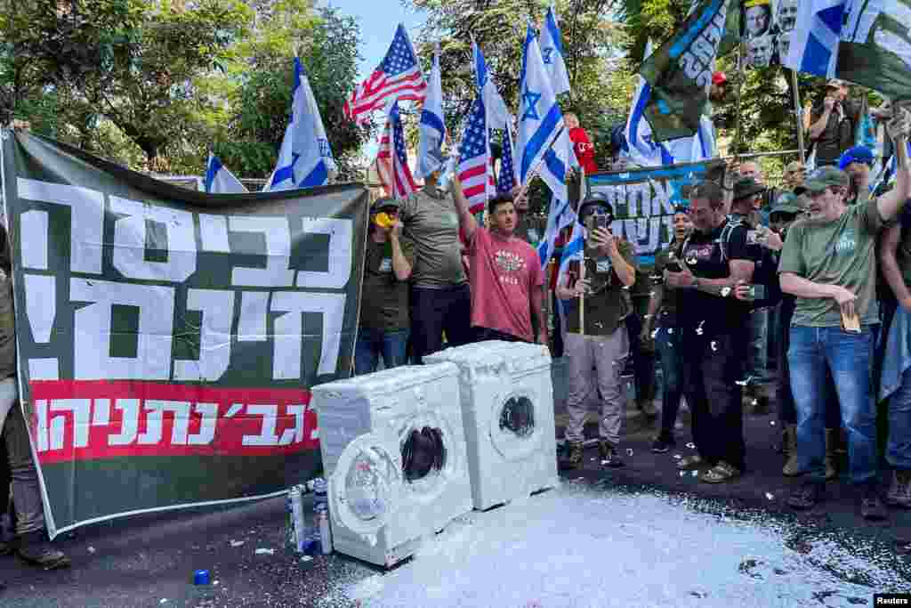 Members of Israel's military reservists hold a banner with the words "free laundry for Mrs. Netanyahu" as part of a stunt outside of Israeli Prime Minister Benjamin Netanyahu's residence to demonstrate against his nationalist coalition government's judicial overhaul, in Jerusalem.