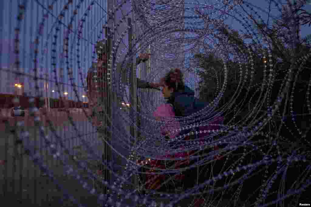 Eliana, 22, a migrant from Venezuela, holds her three-year-old daughter Chrismarlees as she shouts towards an Army National Guard soldier after he halted her from breaching a razor wire-laden fence along the bank of the Rio Grande river in El Paso, Texas, March 26, 2024.