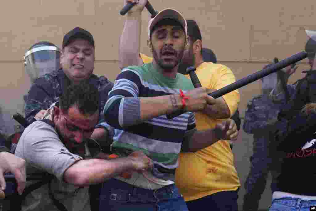 Bank security personnel and riot police attack an injured protesting depositor outside a Bank Audi branch in downtown Beirut, Lebanon. Depositors for years have protested at the banks, demanding their trapped savings back, as they struggle amid an economic crisis that has plunged upwards of three-quarters of the tiny country's population into poverty.