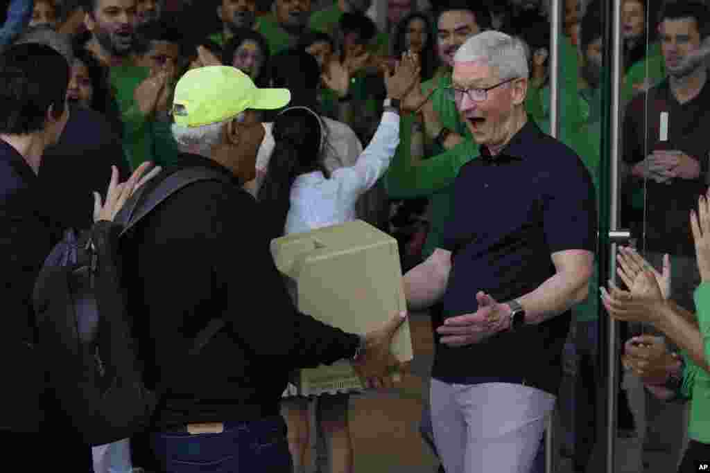 Apple CEO Tim Cook, right, reacts after seeing an old old Macintosh Classic machine brought by a visitor during the opening of the first Apple Inc. flagship store in Mumbai, India.