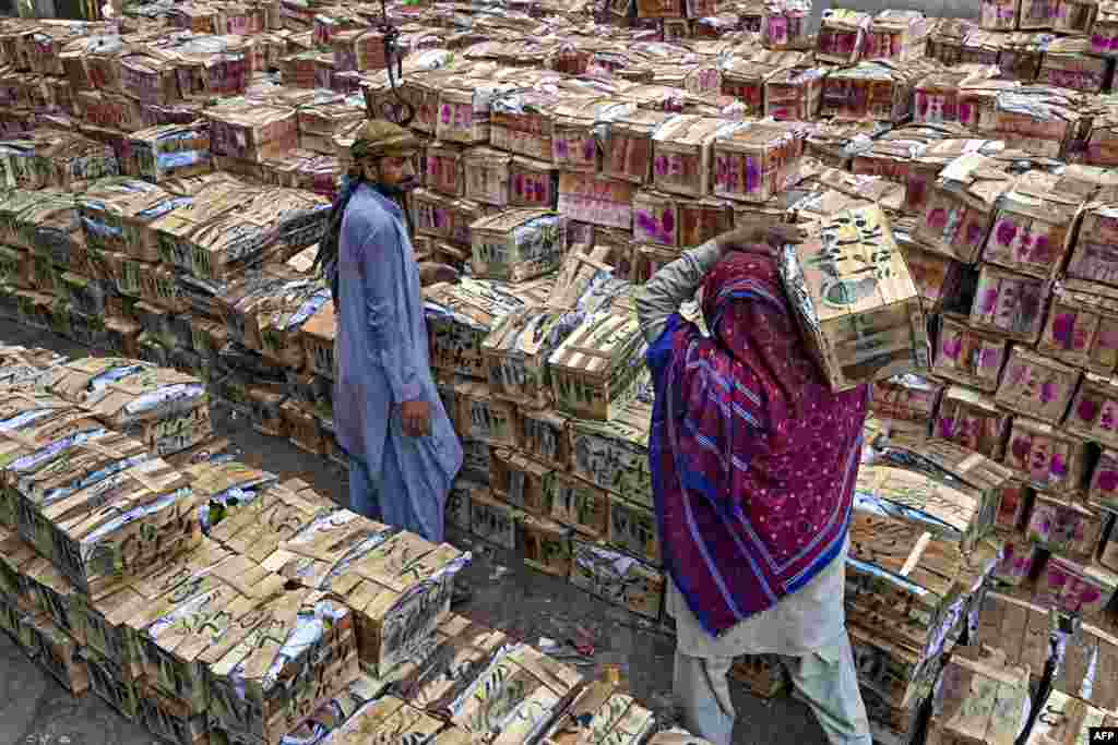 A laborer carries a mango crate at a market in Lahore, Pakistan.