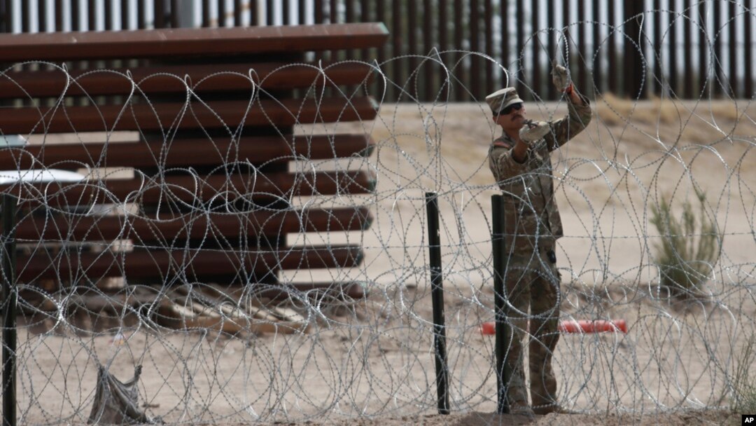 A member of the Texas National Guard installs a barbed-wire barrier on the border between El Paso, Texas and Ciudad Juárez, as seen from Ciudad Juárez, Mexico, May 3, 2023.