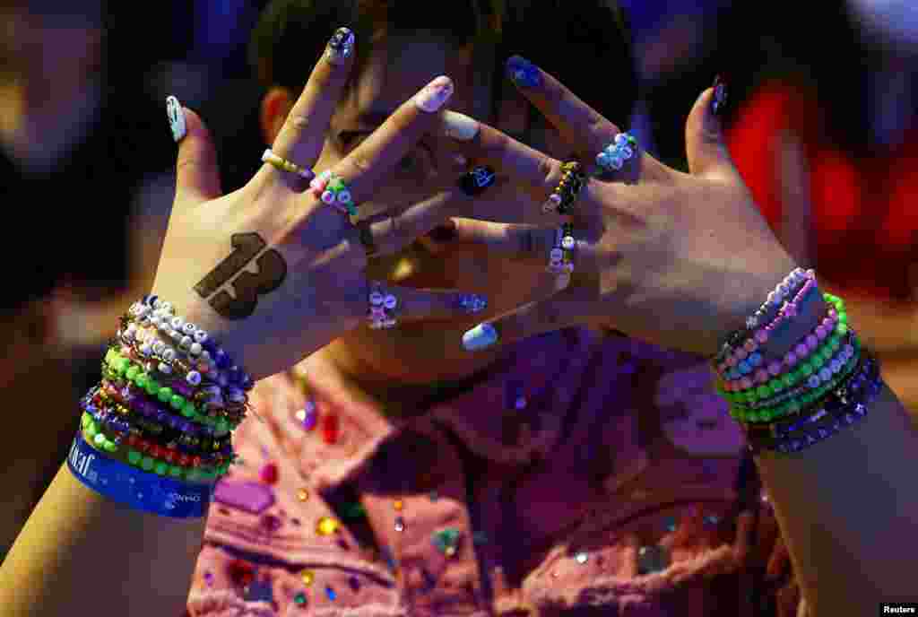 Luke, 22, from Shandong, China, shows his bracelets amid Taylor Swift fans, or Swifties, during a sing-a-long ahead of Swift's Eras Tour concert, at Jewel Changi Airport in Singapore.