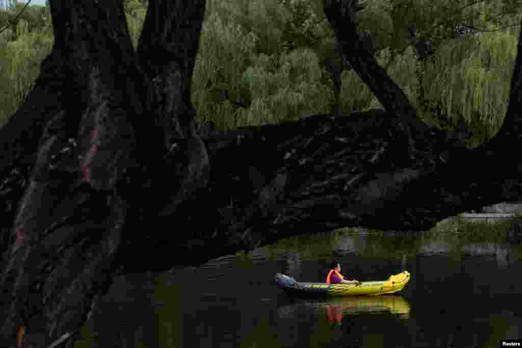 A woman sits in an inflatable boat on a canal to cool off on a hot day in Beijing, China.