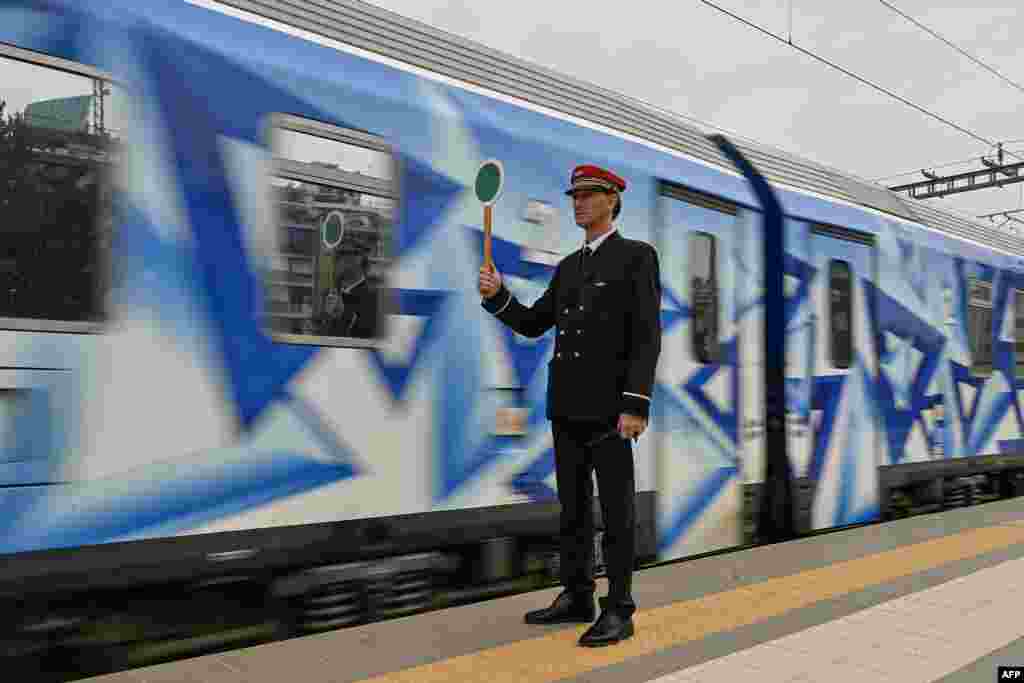 A station master holds a signaling disc as the first train since a deadly train disaster leaves from Athens' main station to Thessaloniki, Greece. Five weeks after the train disaster that killed 57 people, the rail link between Athens and Thessaloniki, the second-largest city in northern Greece, has partially resumed. 