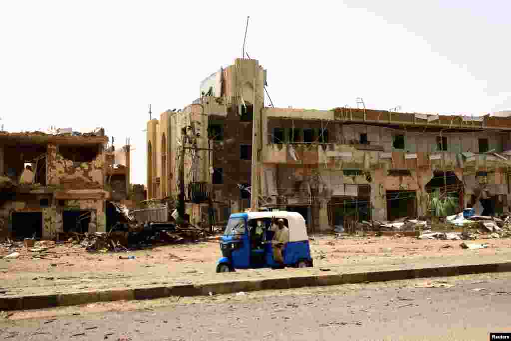 People pass by damaged cars and buildings at the central market during clashes between the paramilitary Rapid Support Forces and the army in Khartoum North, Sudan.
