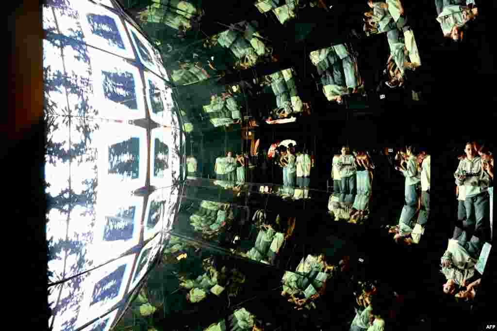 Students are reflected in mirrors as they stand in front of a projection during their visit of the Lumia interactive exhibition of digital art, in Prague, Czech Republic.