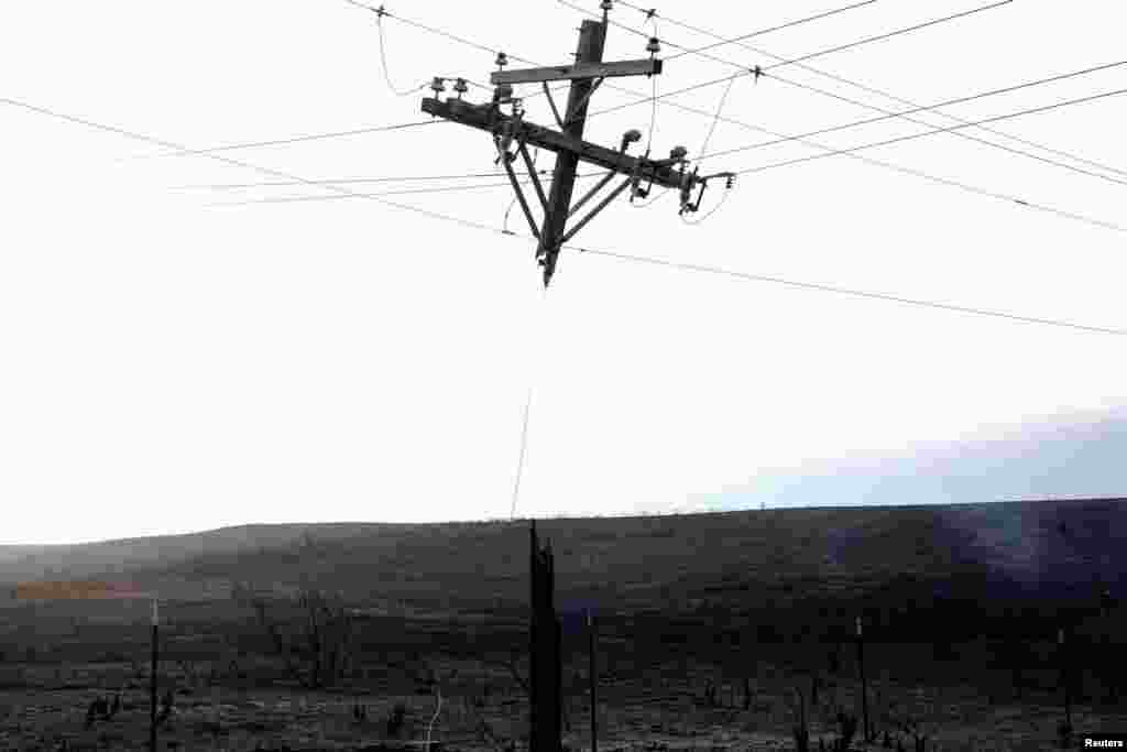 A power pole that was burned by the Smokehouse Creek wildfire hangs from the power lines in Canadian, Texas.