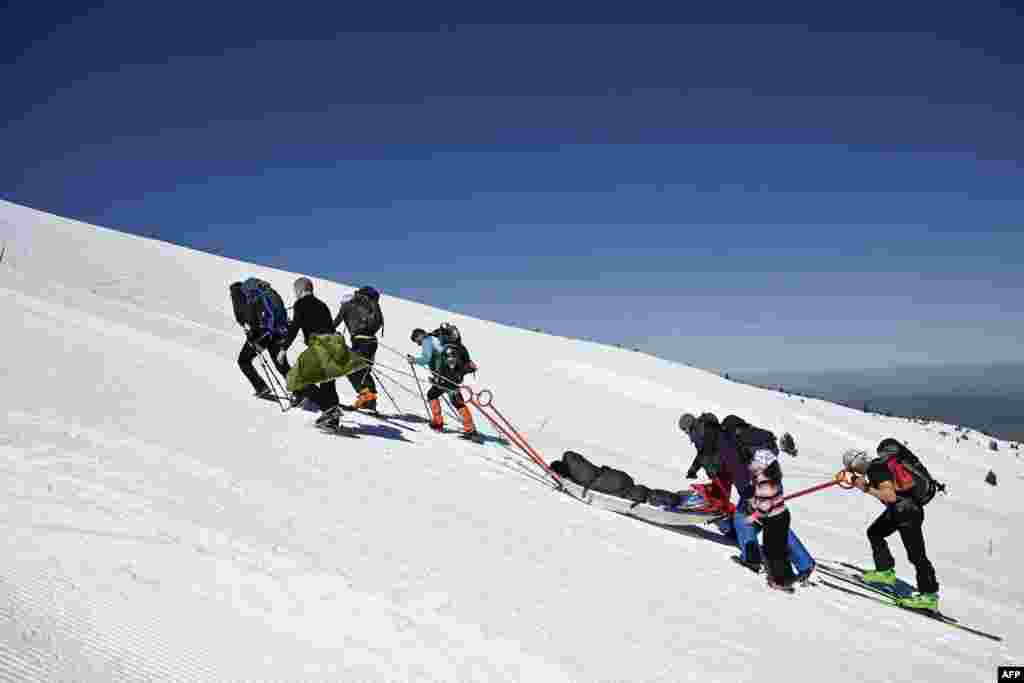 Volunteers pull a person with disabilities on a snow stretcher at 2507 meter high as they climb the Rila Mountain, southwestern Bulgaria, March 23, 2024. More than 50 volunteers came together to help five people with various disabilities to reach the snow-covered peaks of the Rila Mountain.