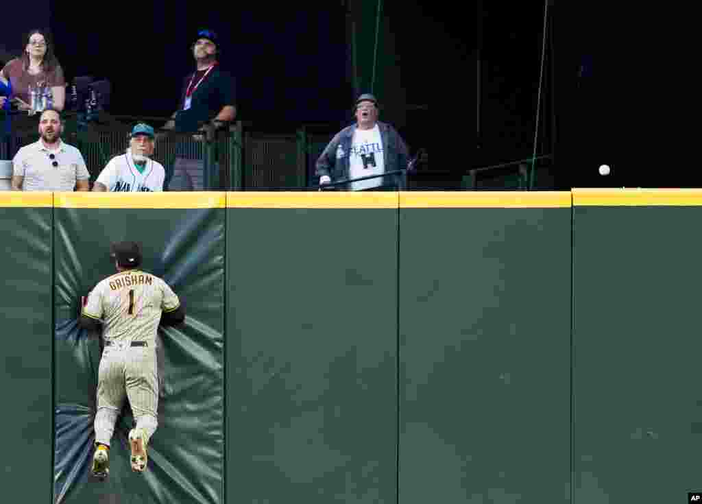 San Diego Padres center fielder Trent Grisham collides with the wall as the RBI triple from Seattle Mariners' Dylan Moore rolls along the top of the wall during the sixth inning of a baseball game Aug. 8, 2023, in Seattle, Washington. 