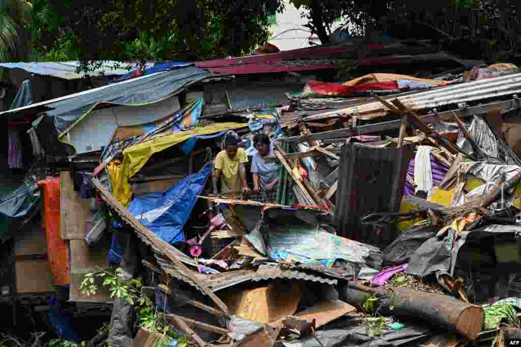 Residents inspect the damage after a huge tree fell on informal settler homes along a creek in Manila, Philippines.