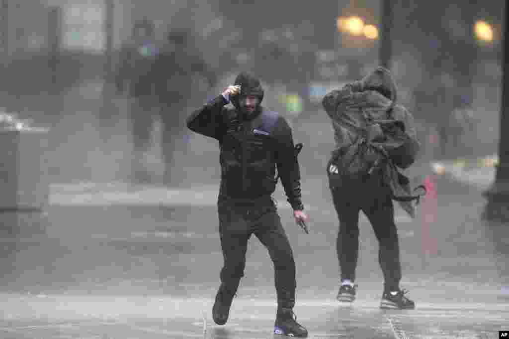 Pedestrians are buffeted by wind and rain as they cross a street in Boston, Massachusetts.