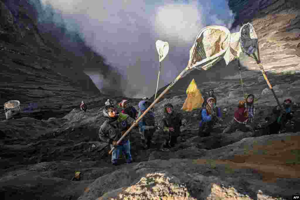 Villagers catch offerings thrown by members of the Tengger sub-ethnic group in the crater of the active Mount Bromo volcano as part of the Yadnya Kasada festival in Probolinggo, East Java province, Indonesia.