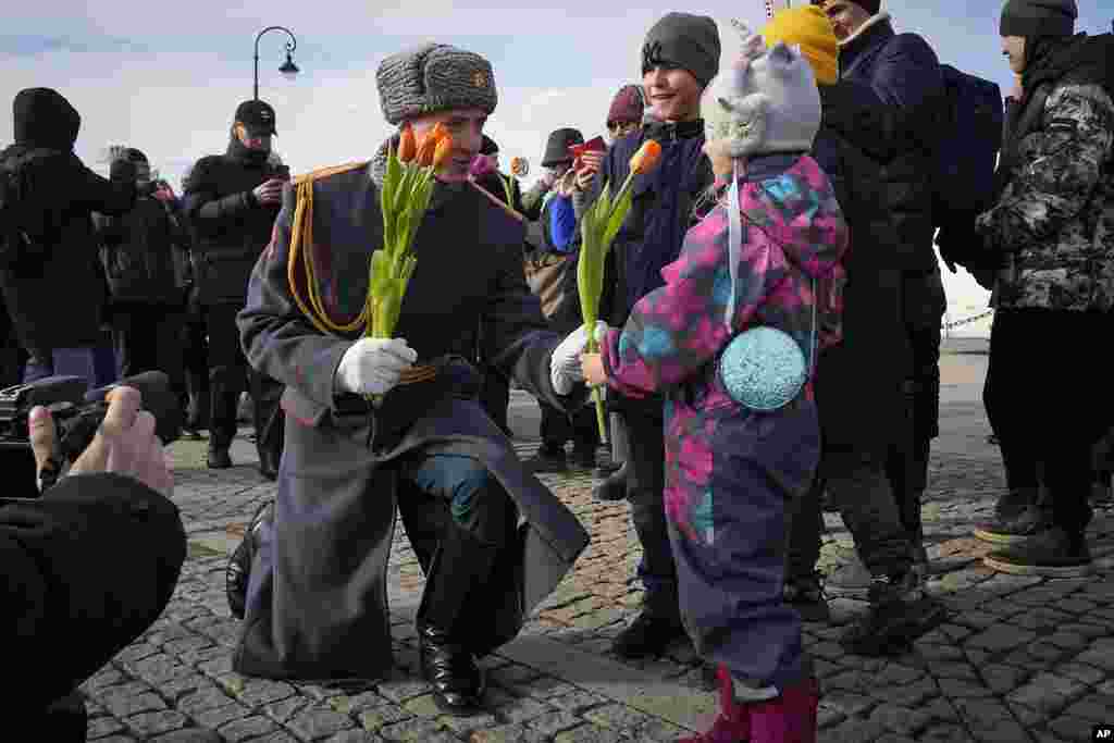 A honor guard soldier gives a flower to a girl on International Women's Day in St. Petersburg, Russia. International Women's Day on March 8 is an official holiday in Russia. Per tradition, men give flowers and gifts to female relatives, friends and colleagues.