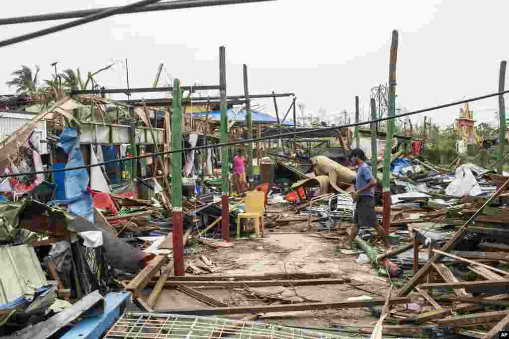 Local residents walk past damaged buildings after Cyclone Mocha in Sittwe township, Rakhine State, Myanmar.