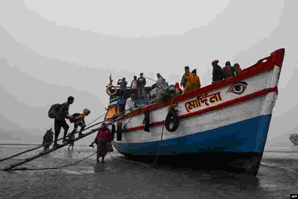 Hindu pilgrims board a boat at the confluence of River Ganges and the Bay of Bengal after attending the Gangasagar mela in Sagar Island, some 150 kms South of Kolkata, India.