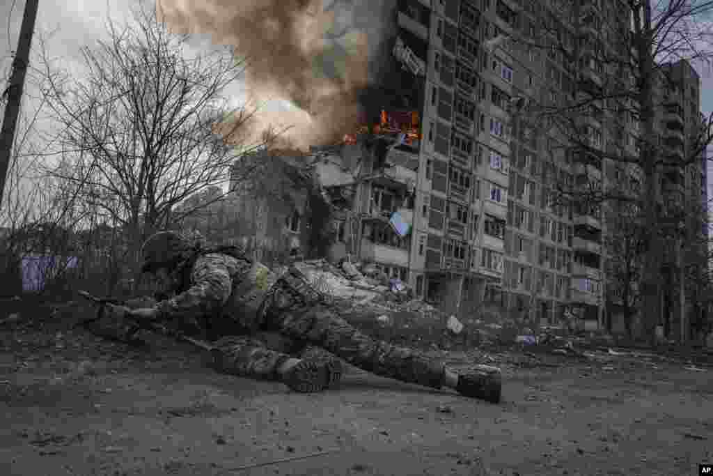 A Ukrainian police officer takes cover in front of a burning building that was hit in a Russian airstrike in Avdiivka, Ukraine, March 17, 2023.