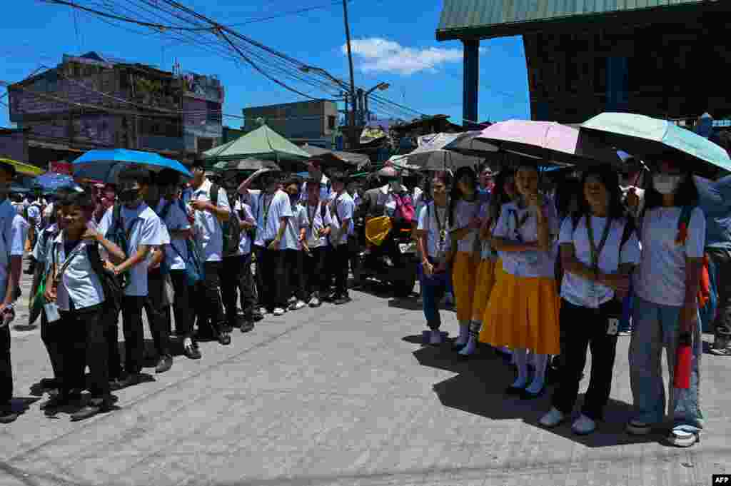 Students use umbrellas to protect themselves from the sun as they line up to wait for their classes outside their school in Manila, Philippines. More than100 schools in the capital shut their classrooms, as the tropical heat hit "danger" levels, education officials said.