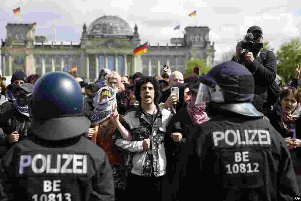 Demonstrators hold together in front of the Reichstag building housing the Bundestag (lower house of parliament) as police officers clear a pro-Palestinians camp of protesters settled near the Federal Chancellery in Berlin, Germany.