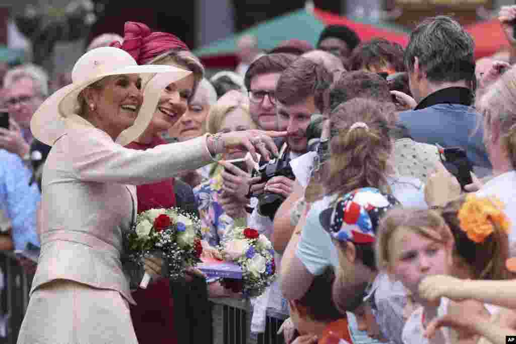 Dutch Queen Maxima, second left, and Belgium's Queen Mathilde, left, greet the crowd at the Grand Place in Brussels, Belgium.