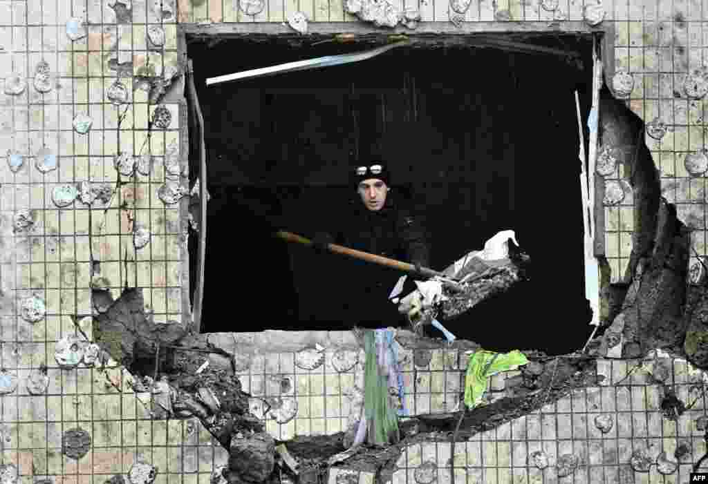 A local resident clears debris from an apartment at a heavily damaged residential building, three days after a Russian missile attack in Kyiv.