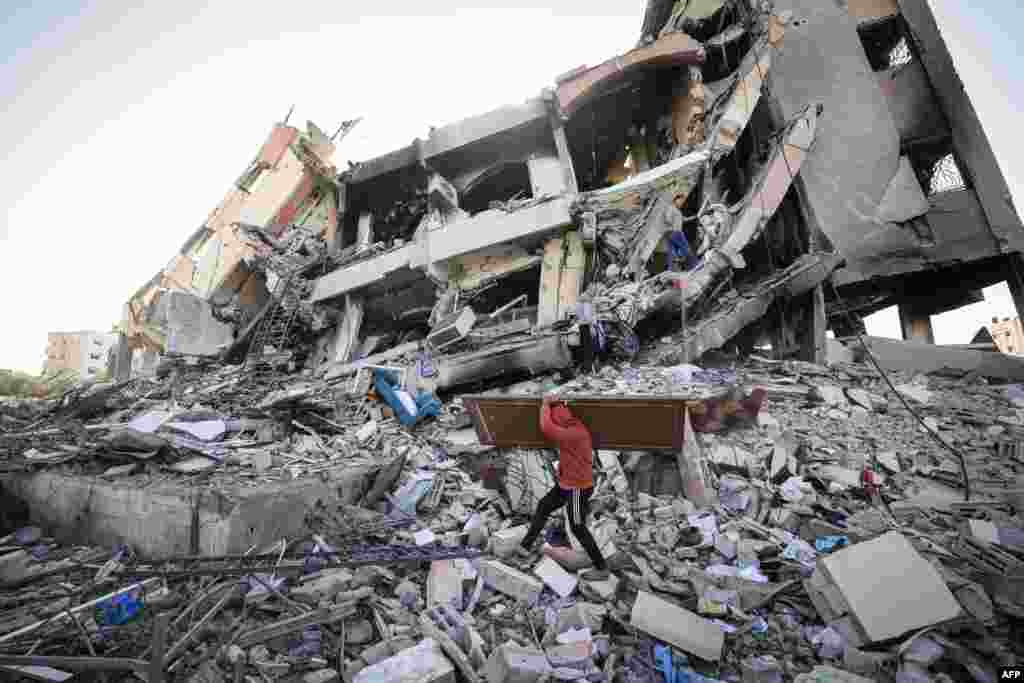 Palestinians carrying some belongings walk amid the rubble of destroyed buildings in Al-Zahra on the southern outskirts of Gaza City as a truce between Israel and Hamas entered its third day.