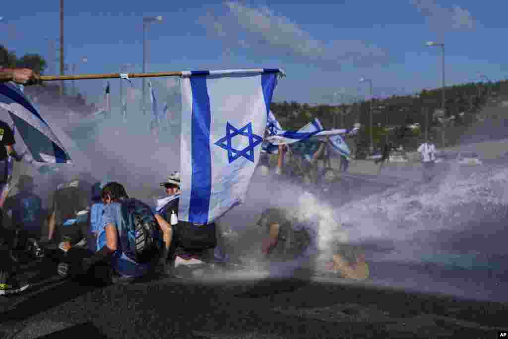 Israeli police use a water cannon to disperse demonstrators blocking a highway leading to Jerusalem during a protest of plans by Prime Minister Benjamin Netanyahu's new government to overhaul the judicial system.