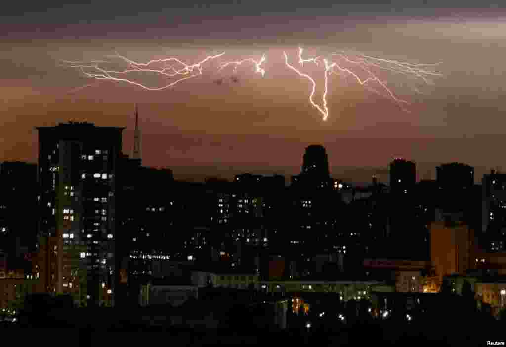 Lightnings are seen over the city during a rain in Kyiv, Ukraine, July 26, 2023.
