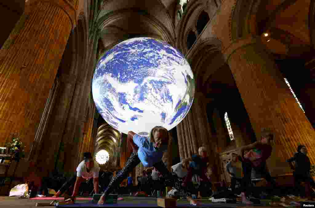 People participate in the Iyengar Yoga Class underneath Luke Jerram's Gaia artwork at Durham Cathedral in Durham, Britain.