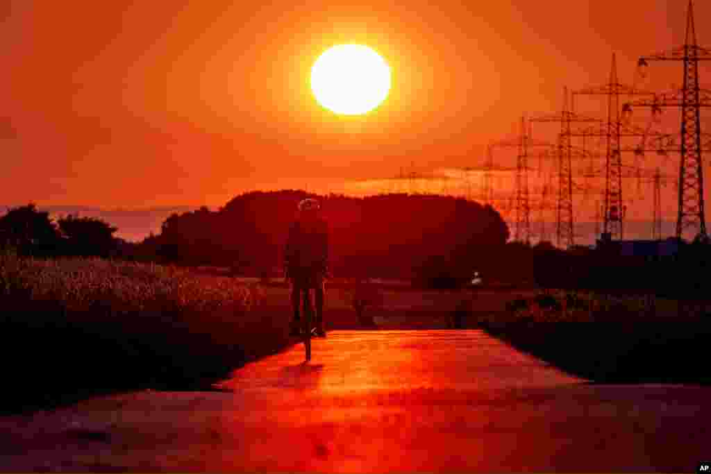 A man rides his bike on a small road in the outskirts of Frankfurt, Germany, as the sun rises.