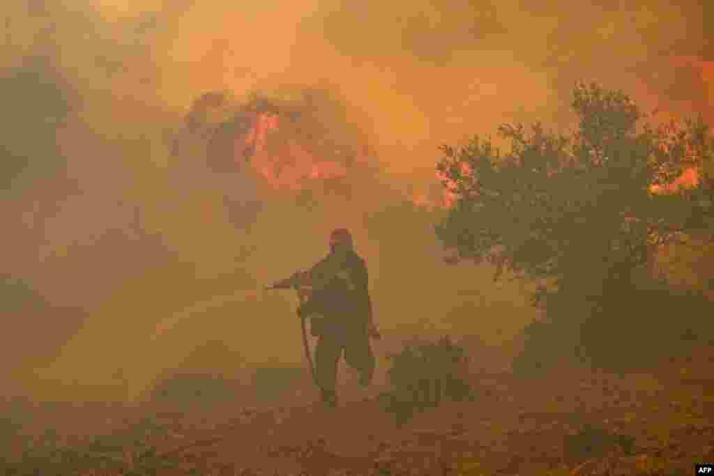 A fireman runs away from blazes as he tries to control a wildfire in New Peramos, near Athens, Greece. Firefighters battled blazes in parts of Greece and the Canary Islands, while Spain issued heat alerts and some children in Italy's Sardinia were told to stay away from sports.