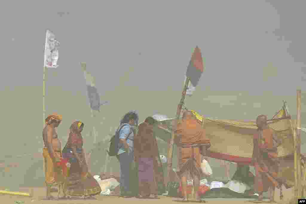 Hindu devotees walk during a sandstorm at the Sangam, the confluence of the rivers Ganges, Yamuna and mythical Saraswati, in Prayagraj, India.