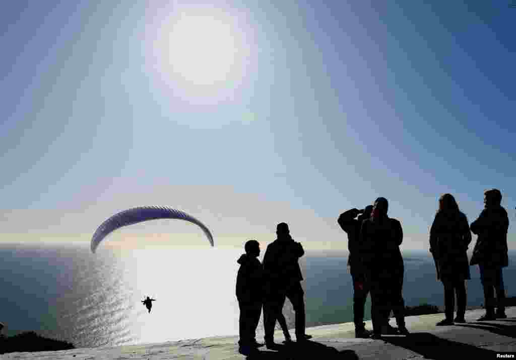 People watch as a paraglider flies near Signal Hill, in Cape Town, South Africa.
