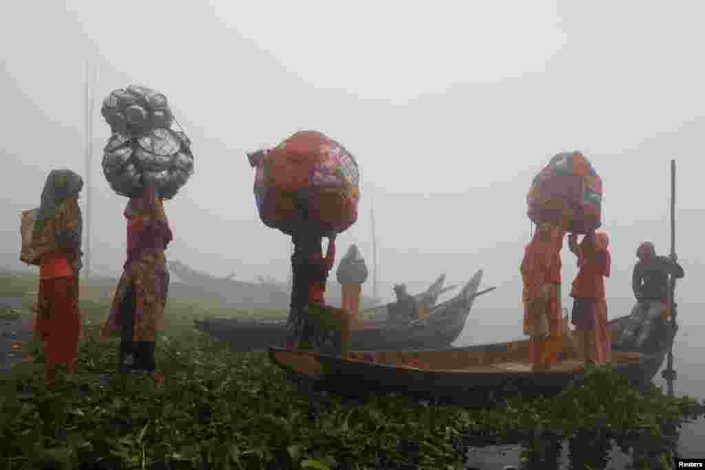 Female hawkers carry plastic and aluminium utensils to sell on a foggy morning in Dhaka, Bangladesh.