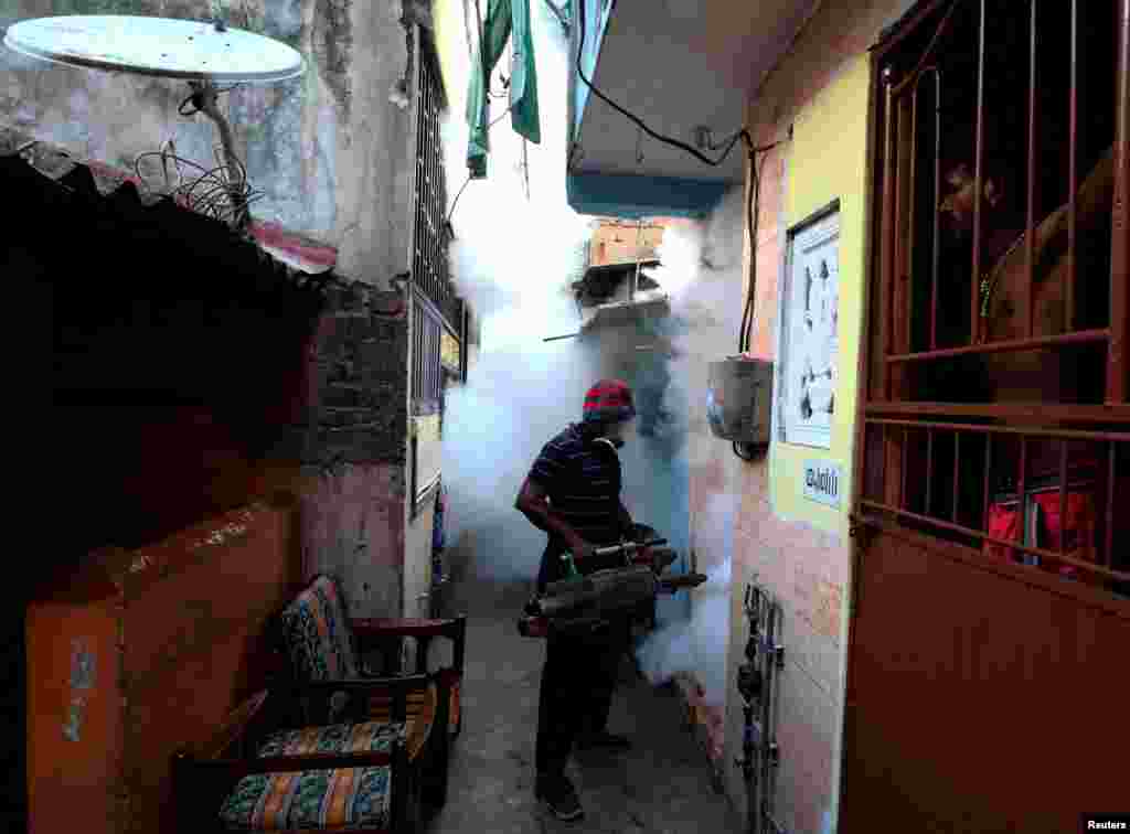 A resident looks on while a health worker fumigates a building in a residential area, as Sri Lanka tries to curb dengue fever across the island in Colombo.