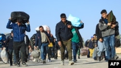 FILE - Afghan immigrants deporting back from Iran, carry their belongings at a registration center in the Islam Qala border town of Herat province on Nov. 6, 2023.