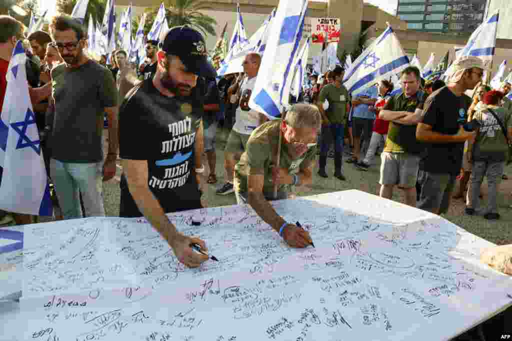 Israeli military reservists sign a declaration announcing the suspension of their voluntary reserve duty, to protest the government's judicial overhaul bill, in Tel Aviv.