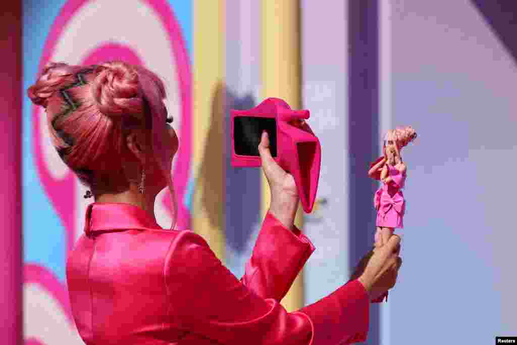 A fan takes a photo of a Barbie doll at the world premiere of the film &quot;Barbie&quot; in Los Angeles, California, July 9, 2023.