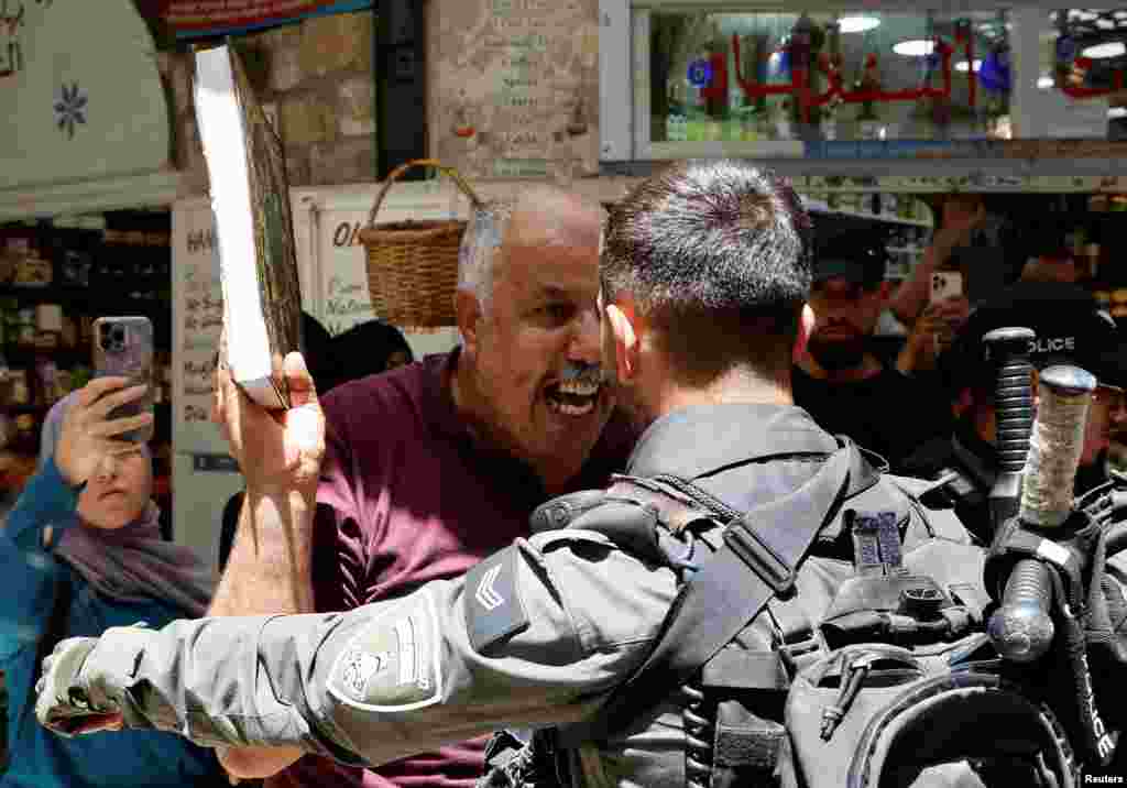 A man holds a copy of the Quran as Israeli police blockade the entrance to the Al-Aqsa Mosque compound following a visit to the site by Israel's hard-right National Security Minister Itamar Ben-Gvir, in Jerusalem's Old City.