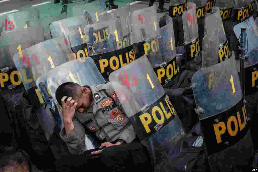 A policeman rests during a demonstration demanding the impeachment of Indonesia's President Joko Widodo, the rejection of the general election results and the removal of members of the General Election Commission, at the entrance of the parliament in Jakarta, March 5, 2024.