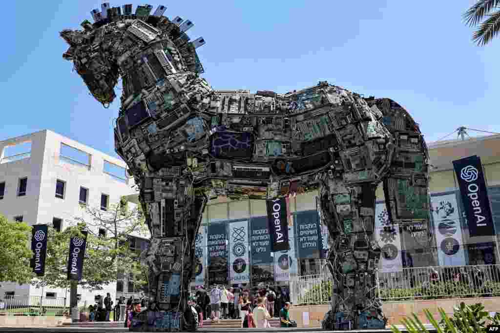 Banners of U.S. artificial intelligence company OpenAI fly near an installation depicting the legendary "Trojan horse" built entirely out of microelectronic circuit boards and other computer components, outside at the campus of Tel Aviv University in Tel Aviv, Israel.
